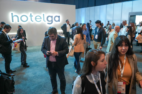 Público recorriendo el evento Hotelga, la exposición líder de hotelería y gastronomía, con el logo institucional iluminado en el área principal.