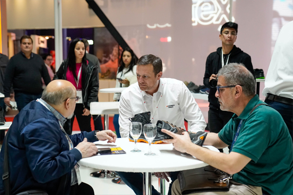 3 hombres sentados alrededor de una mesa haciendo negocios en la exsición