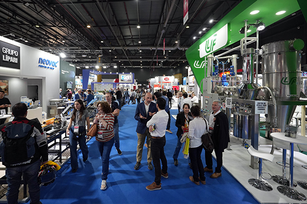 Vista amplia de la exposición con numerosos asistentes caminando por los pasillos y visitando diferentes stands.