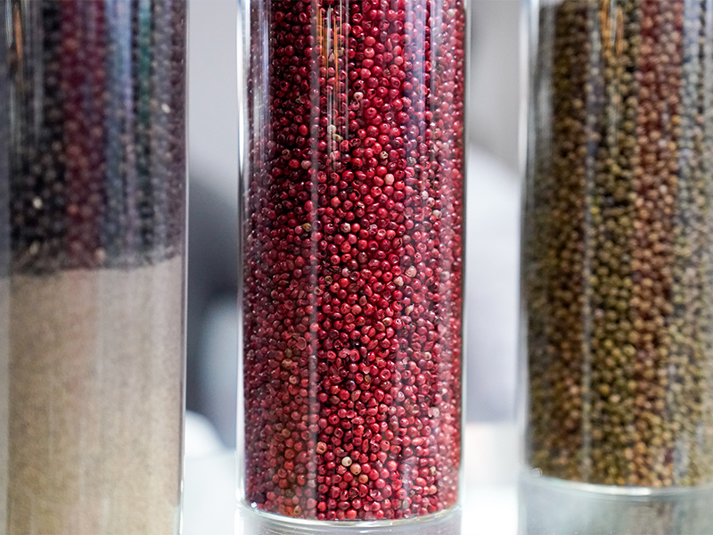Frascos de vidrio con granos de pimienta roja y otras especias