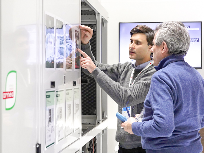 Dos hombres, uno de ellos señalando con el dedo, examinando una máquina de refrigeración industrial en Tecno Fidta