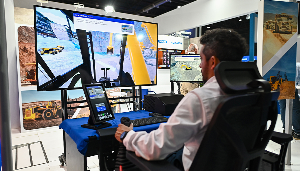 Simulador de maquinaria minera exhibido en un stand de la exposición Arminera, con pantalla interactiva y tecnología aplicada a la operación del sector.